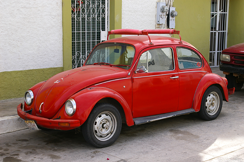 A red vintage beetle car on the pavement. 