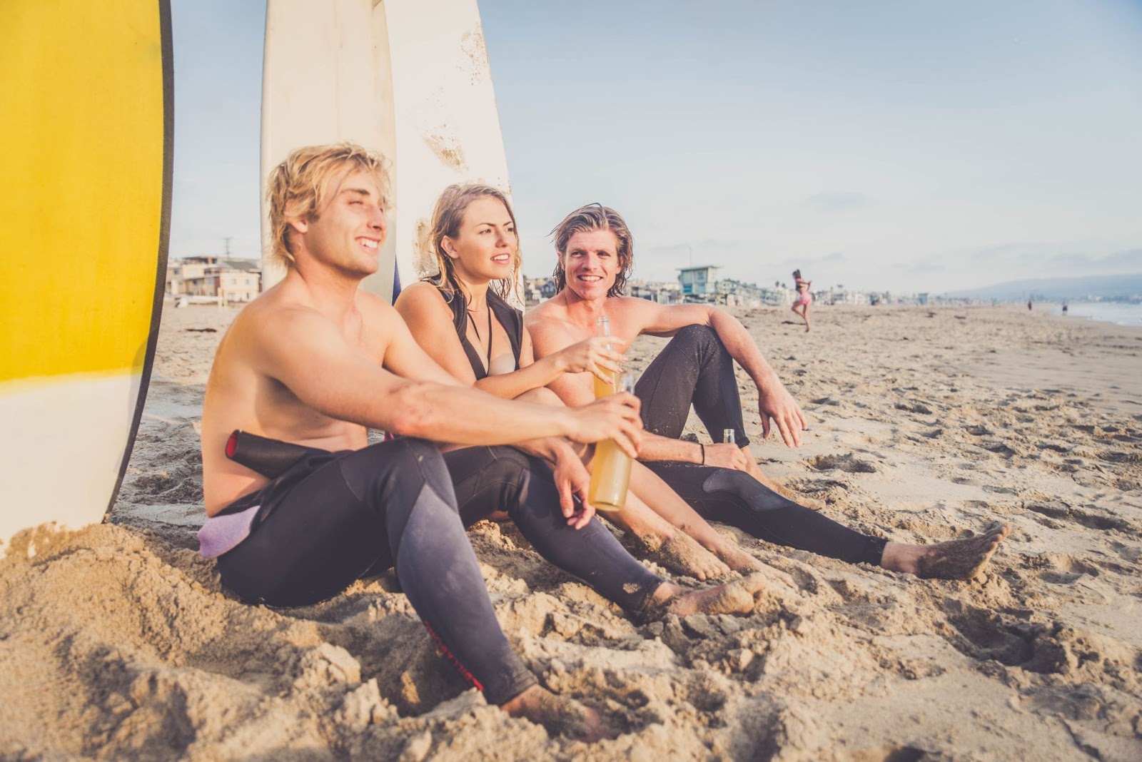 Three surfers sitting on beach