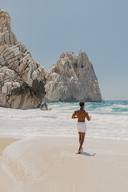 Shirtless man walking towards the sea