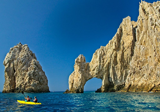 a yellow kayak kayaking in front of El Arco los Cabos 